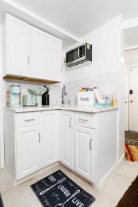 eine Küche mit weißen Schränken und einer Mikrowelle in der Unterkunft Exquisite in Brooklyn