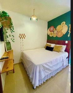 a bedroom with a white bed with a painting on the wall at AP1 Atrás da passarela do caranguejo - Orla de Atalaia in Aracaju