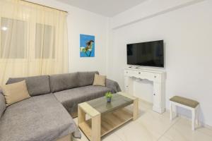 een woonkamer met een bank, een tv en een tafel bij Filocsenia luxury apartment at tsoutsouras in Tsoútsouros