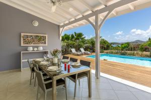 a dining room with a table and chairs and a pool at Villas Palm in Le Vauclin