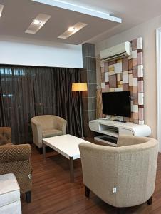 ein Wohnzimmer mit einem TV, einem Sofa und Stühlen in der Unterkunft GS Suite & Homestay in Ipoh