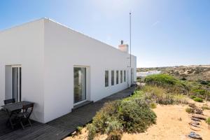 een wit huis met een terras en een tafel bij Sanderling beach & dune house in Carrapateira