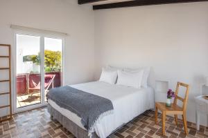 a bedroom with a bed and a table and a window at Sanderling beach & dune house in Carrapateira