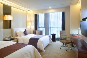 Crowne Plaza Xiangyang, an IHG Hotel في شيانغيانغ: غرفه فندقيه سريرين وتلفزيون