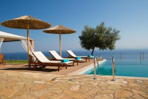 a swimming pool with chairs and umbrellas next to a pool at Thea Thalatta Villas in Tsoukaladhes