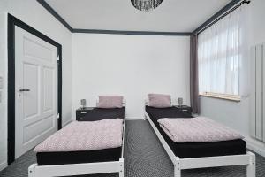 duas camas num quarto com uma porta e uma janela em Anhalt Pension em Coswig