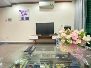 ein Wohnzimmer mit einem TV und einer Vase aus Blumen in der Unterkunft Căn hộ Hoàng Anh DakLak ngay trung tâm BMT gồm 3PN lớn Full nội thất rộng rãi từ 8-10 người in Buon Ma Thuot