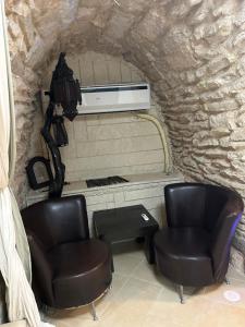 duas cadeiras e uma mesa num quarto com uma parede de pedra em Authentic Tzfat Cave Tzimmer em Safed