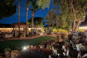 a backyard with a pond and a resort at night at The Arrowhead Oasis - hot tub, heated pool, fire pits, backyard games in Glendale