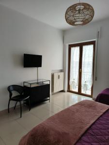 a bedroom with a bed and a chair and a television at Sweet holidays in Matera