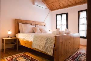 Un dormitorio con una gran cama de madera con almohadas blancas. en Porta7 Hotel en Gjirokastër