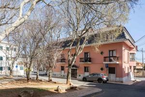 różowy budynek z samochodem zaparkowanym przed nim w obiekcie Casa Paraíso Cascais w mieście Cascais