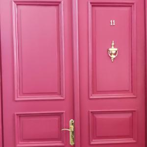a pink door with a brass knocker on it at Ventspils apartamenti pie Rātslaukuma in Ventspils