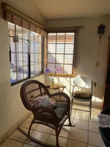 a room with a chair and a table and two windows at Casa Gaviotas Art cozy 2 bed house with art studio close to downtown in La Paz