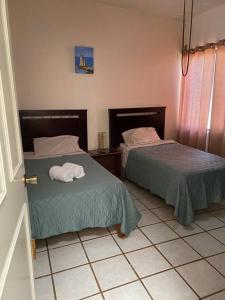 a room with two beds with towels on them at Casa Gaviotas Art cozy 2 bed house with art studio close to downtown in La Paz