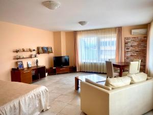a living room with a couch and a table and a television at Arena Tarnovo Hotel -Free Large Private Parking in Veliko Tŭrnovo