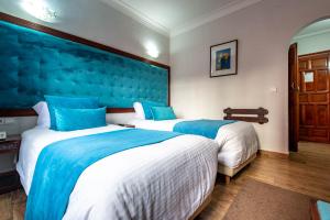 2 camas en una habitación de hotel con paredes azules en Hotel Oudaya & Spa, en Marrakech