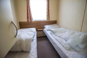 2 camas en una habitación pequeña con ventana en 8 Berth Spacious Caravan By The Beach In Norfolk Ref 50059g en Great Yarmouth