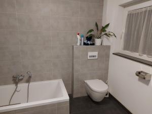 y baño con aseo, bañera y lavamanos. en Several different rooms, newly furnished, in a new house in Vichten, en Vichten