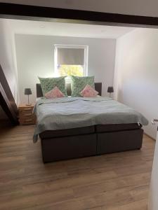 a bedroom with a large bed with green and pink pillows at Lieblingsplatz an der Lahn in Weinbach