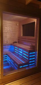 a sauna with a tv and blue lights in it at Sjesta al mare, domki z sauną i balią z jacuzzi in Lubiatowo