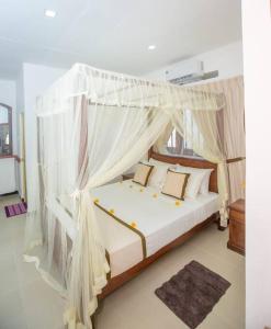 a bedroom with a white canopy bed with pillows at Greenway Apartment in Galle