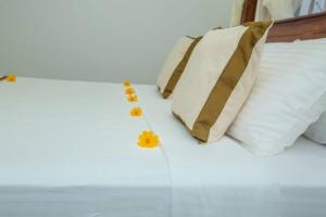 a bed with white pillows and yellow flowers on it at Greenway Apartment in Galle