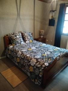 Un dormitorio con una cama con una manta con flores en maison en Périgord proche Beynac et Sarlat en Cénac-et-Saint-Julien