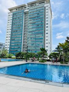 a woman swimming in a pool in front of a tall building at Queen Size Studio in Solinea, Cebu City in Cebu City