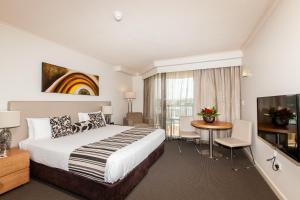 a hotel room with a bed and a table and a television at Central Cosmo Apartment Hotel in Brisbane