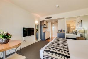 a living room with a bed and a dining room at Central Cosmo Apartment Hotel in Brisbane