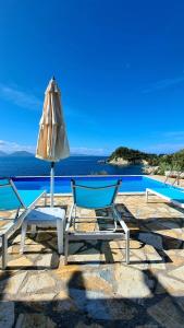 two chairs and an umbrella next to a pool at Amousso Beach Villas in Marantochori