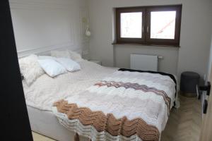 a bedroom with a large white bed with a window at Apartament na Helskiej in Rewa