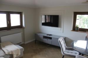 a living room with a television and a table and chairs at Apartament na Helskiej in Rewa