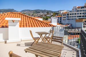 Un patio con dos sillas y una mesa en un balcón. en Apartamentos Progresso 1º Esq, en Funchal