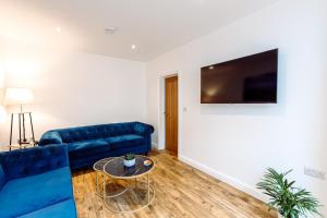 uma sala de estar com um sofá azul e uma televisão em Chute House 4 bed house private garden city center em Exeter