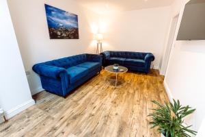 a living room with two blue couches and a table at Chute House 4 Bed House Private Garden City Ccenter in Exeter