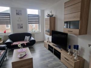 ein Wohnzimmer mit einem TV, einem Sofa und einem Stuhl in der Unterkunft Küstenliebe in Bremerhaven