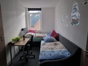 a room with two beds and a desk and a window at Küstenliebe in Bremerhaven
