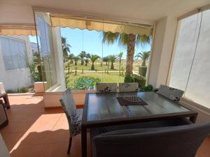 comedor con mesa y sillas y ventana grande en Luxury South Facing Golf Course Apartment & Pool in Roldan, en Las Pedreñas