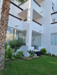 una casa blanca con una palmera en el patio en Luxury South Facing Golf Course Apartment & Pool in Roldan, en Las Pedreñas