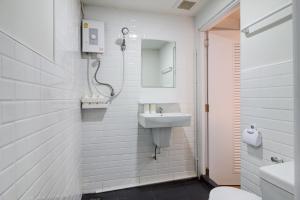 a white bathroom with a sink and a mirror at Bangkok Watergate Townhouse 曼谷中心水門家 in Bangkok
