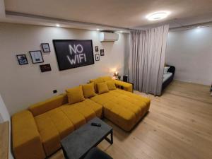 - un salon avec un canapé jaune et un panneau sans connexion Wi-Fi dans l'établissement KELEIA NEW VILLAGE, à Celje