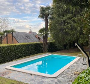 une piscine bleue dans une cour arborée dans l'établissement VSC Apartment - Appartamento in villa storica vista lago e piscina, à Lesa