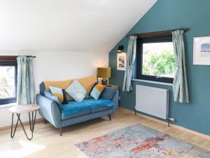 a living room with a blue couch and two windows at Little Fursdon Apartment in Merrymeet