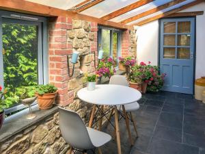 a patio with a white table and chairs and plants at Little Fursdon Apartment in Merrymeet