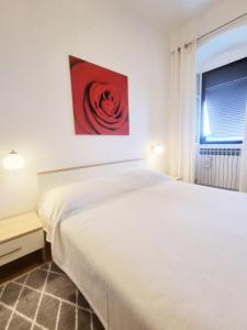 1 dormitorio con 1 cama blanca y una pintura roja en la pared en Apartment Hana, en Ičići