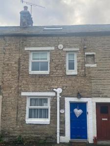 a brick house with a blue door with a heart on it at Kingfisher Cottage in High Bentham