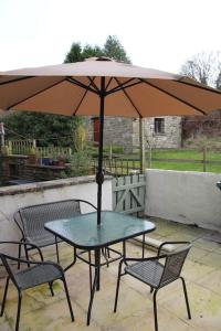 una mesa y sillas con una sombrilla en el patio en Kingfisher Cottage, en High Bentham