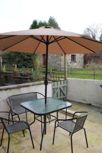 a table and chairs with an umbrella on a patio at Kingfisher Cottage in High Bentham